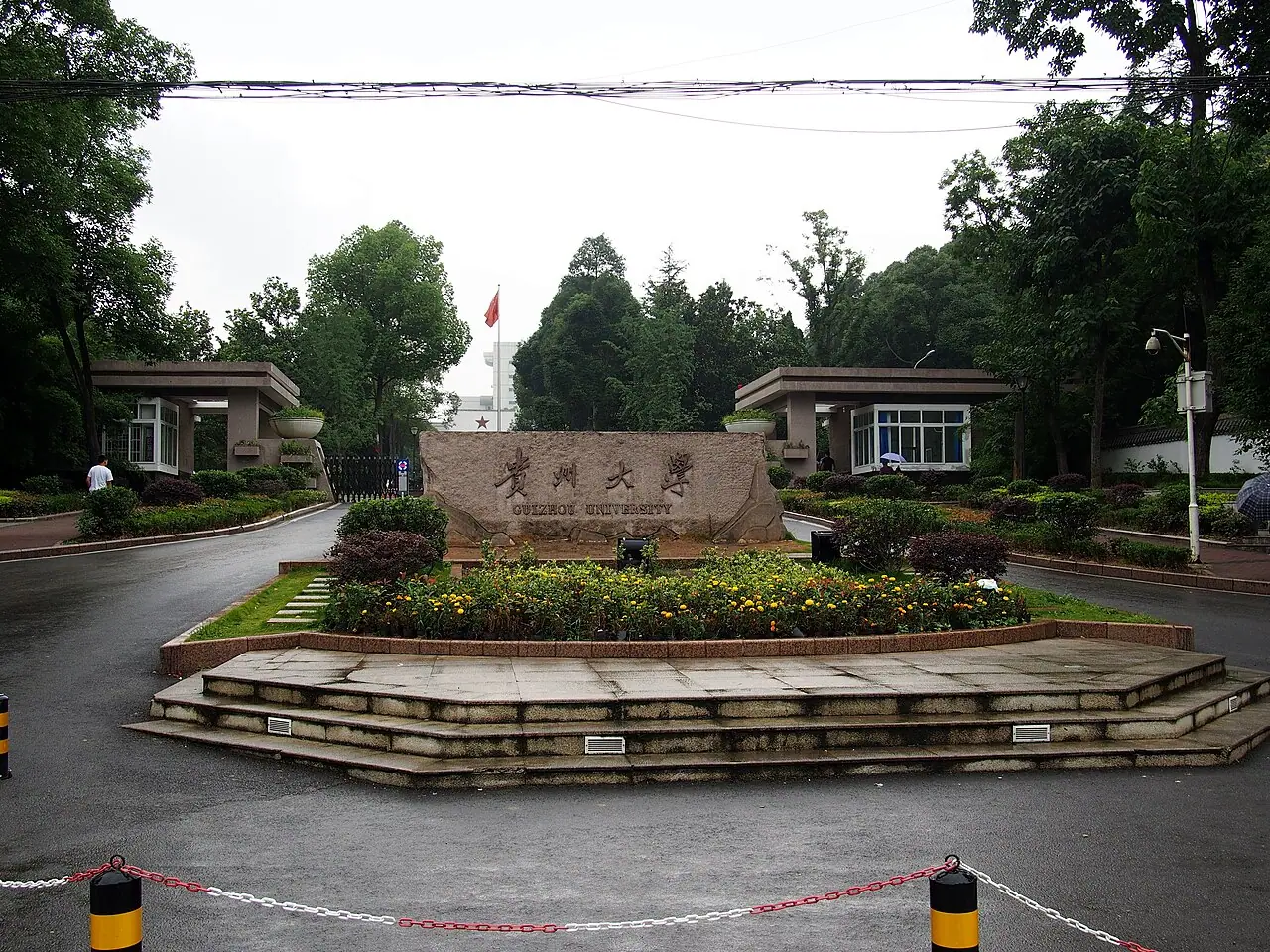 Biển đá mang tên Đại học Quý Châu bên hàng cây và bãi cỏ.