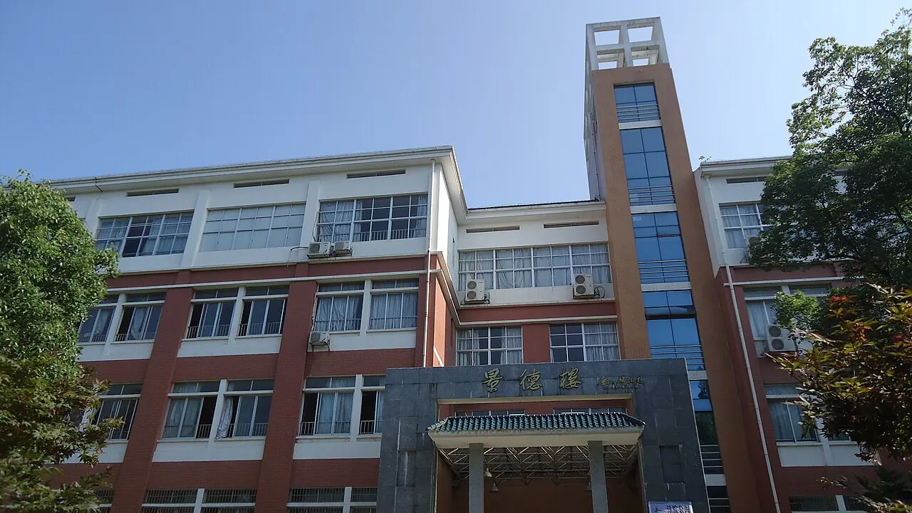 Tòa Cảnh Đức với tháp kính hẹp và hàng cây tại Đại học Sư phạm Hồ Nam.