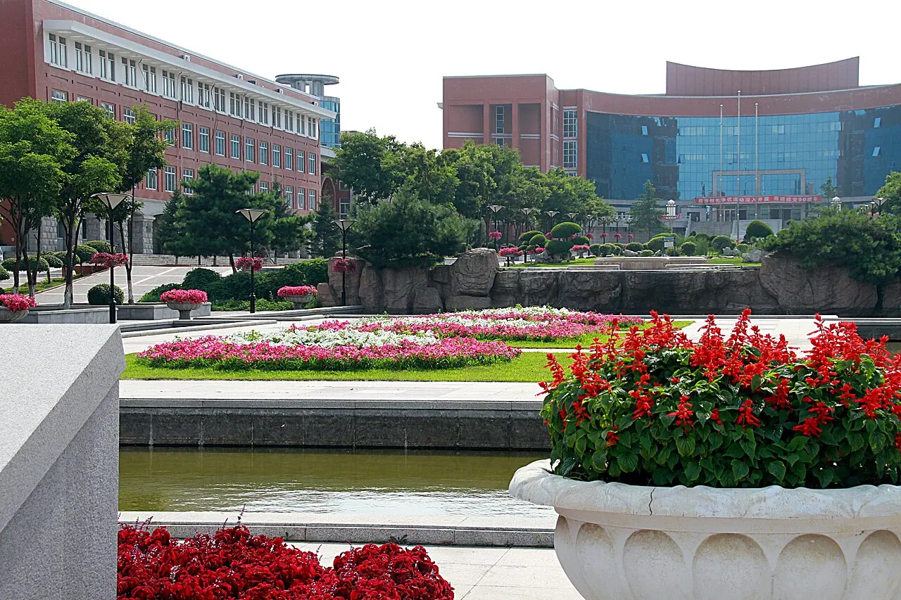 Bồn hoa đỏ, hồ cảnh và lối đi trước các tòa nhà tại cơ sở Jingyue của Đại học Sư phạm Đông Bắc.