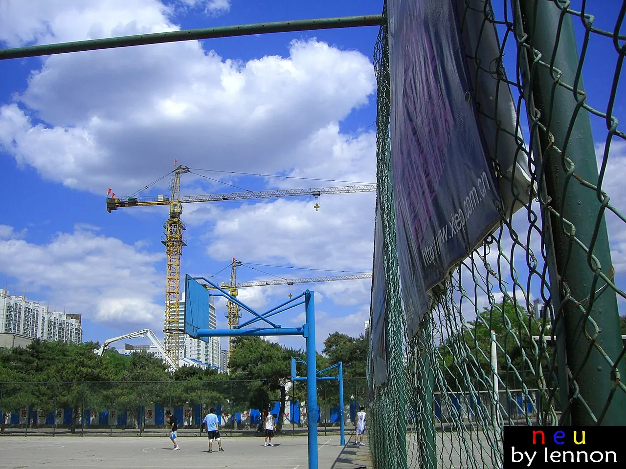 Sân bóng rổ ngoài trời của Đại học Đông Bắc ở Thẩm Dương, phía sau là các tòa nhà và cần cẩu.