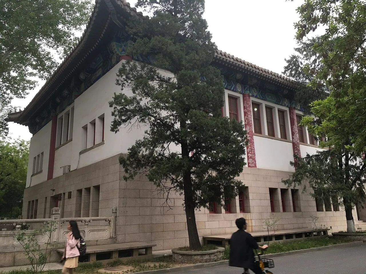 Nhà thi đấu Bao với mái truyền thống bên hàng cây tại Đại học Bắc Kinh.