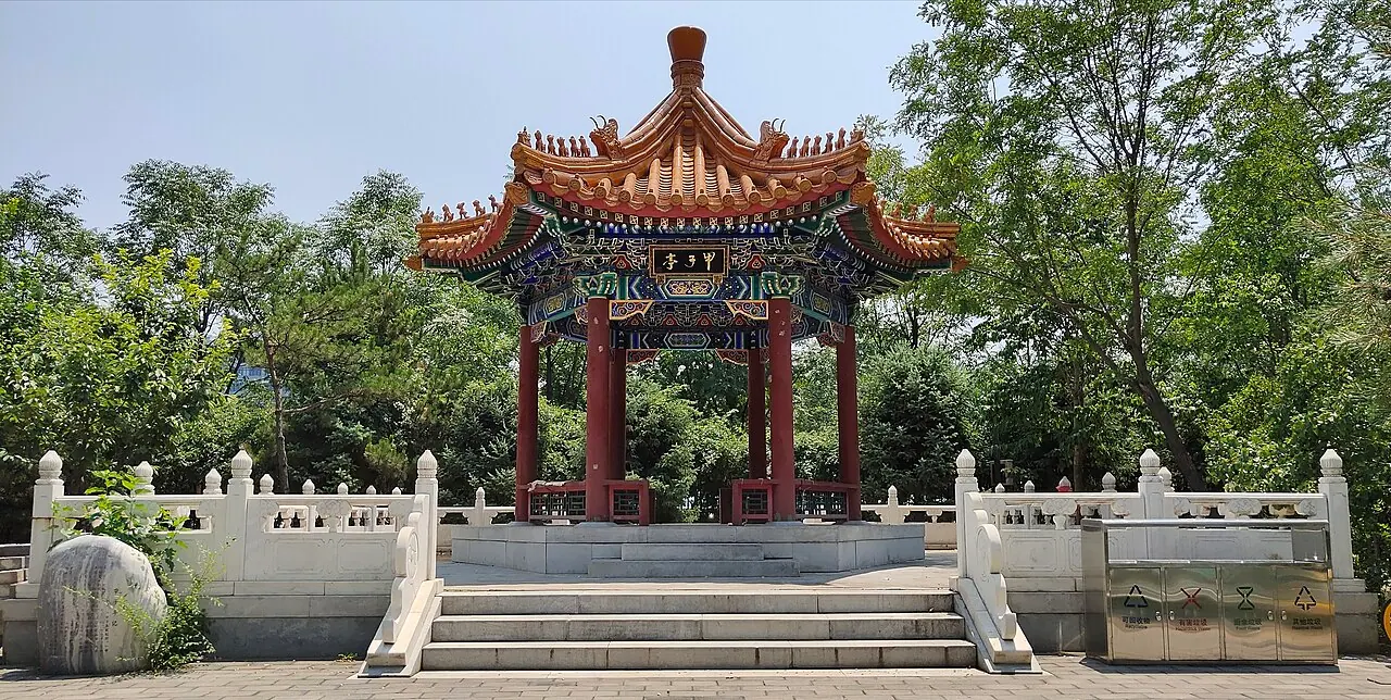Đình Jiazi mái ngói đỏ trang trí nhiều màu, nằm giữa cây xanh và lan can đá.