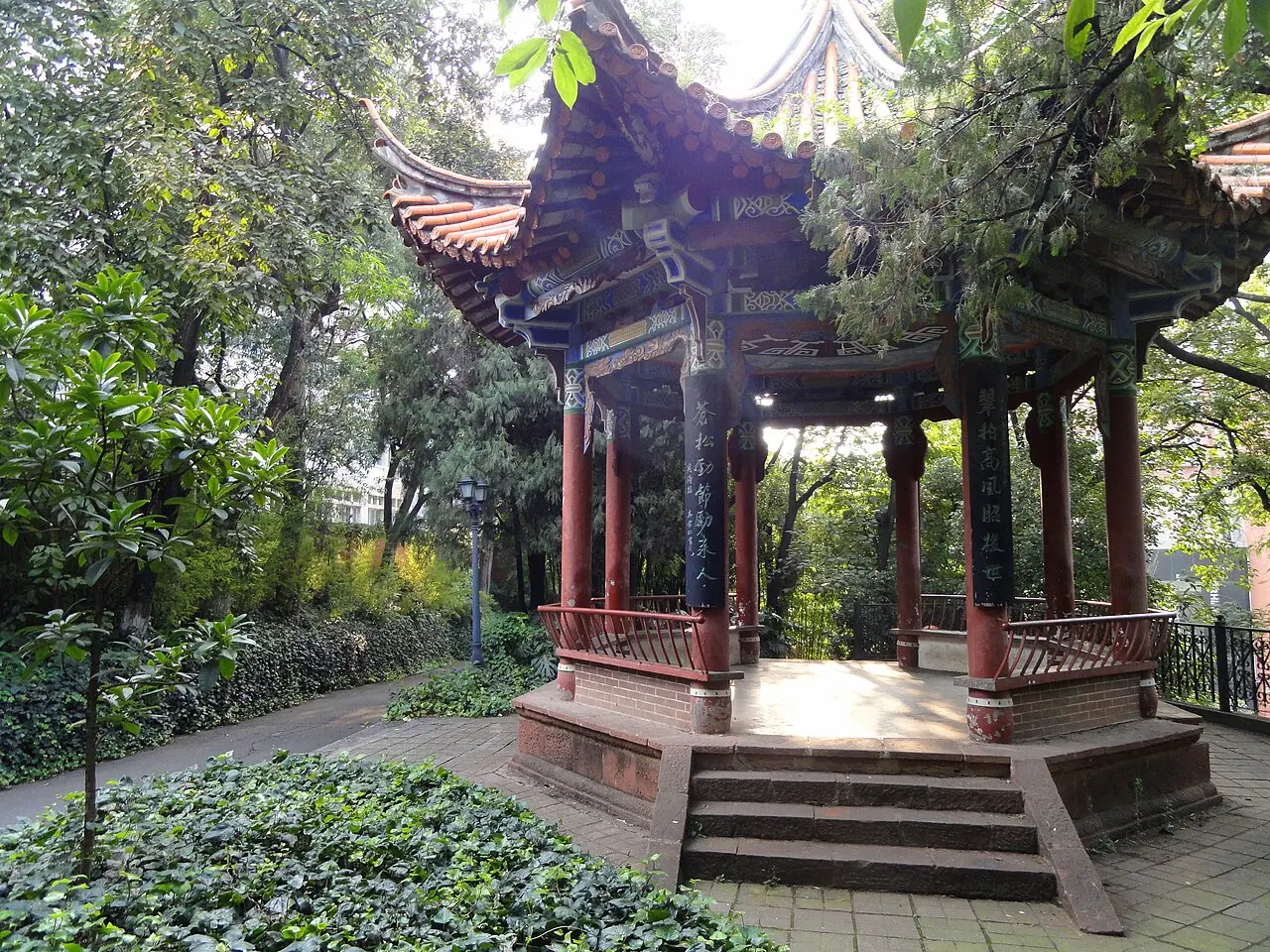 Đình Fengjie mái ngói cong và cột đỏ dưới các tán cây ở Đại học Vân Nam.